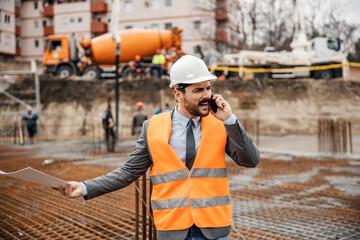 A nervous site manager is arguing with constructors on the phone while standing on site. The works...