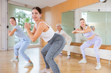 Practiced young woman engaging in aerobics in dance studio during workout session. Women training...