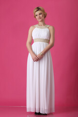 blonde beautiful natural girl with blonde hair in a white dress in the studio room, with makeup and hairstyle, Greek woman in a white ethnic historical dress, retro on a pink background