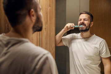 Man is brushing his teeth in a bathroom at night.