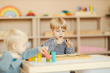 Selective focus on a boy learning motor and logic skills in kindergarten.