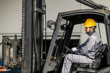 A heavy industry forklift driver is driving in a facility.