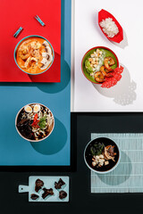 Composition with variety of Asian soup on colorful background, seafood , tom yum, ramen, cream soup with spinach and shrimps , miso soup, salmon, mushrooms