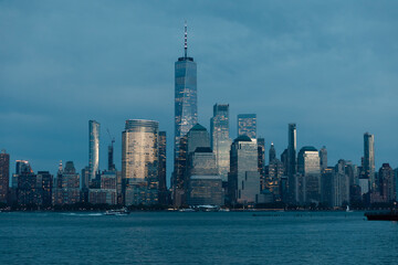 scenic view of Hudson river harbor and skyscrapers of Manhattan financial district in dusk.