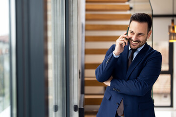 Portrait of handsome businessman using smartphone in modern office