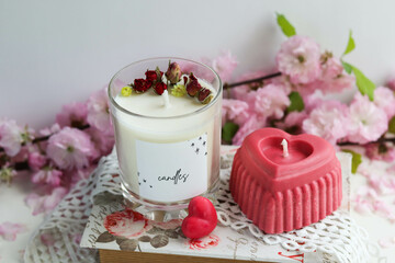 valentine's day background. candle in the shape of a heart made of natural soy wax in the shape of a heart and a bouquet of flowers