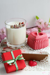 valentine's day background. candle in the shape of a heart made of natural soy wax in the shape of a heart and a bouquet of flowers