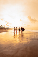 a group of Asian teenagers in shirts running with their friends with very cheerful expressions on the beach