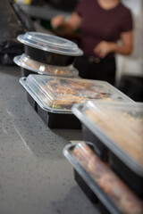 A view of several plastic to-go containers ready for pick up on a restaurant counter.