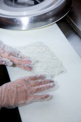A view of a hand preparing a sushi roll at an ingredient station.