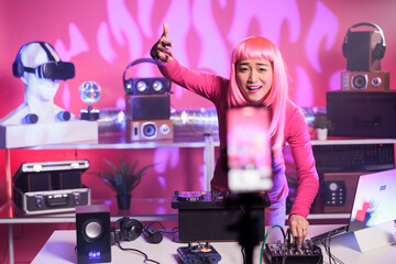 Artist having fun in studio while performing electronic song using professional mixer console recording mixing process with mobile phone camera. Dj woman doing performance at nightclub