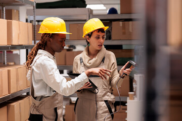 Diverse woman storehouse managers scanning parcels for stock monitoring. Warehouse workers using...