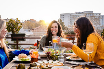 Happy friends having fun eating vegan food outdoor with sunset background - Focus on center girl...