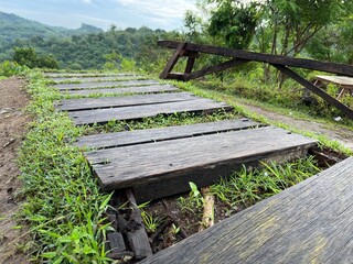 Fototapeta premium Close up view of wooden board for footpath on a hill with panoramic landscape on the background.