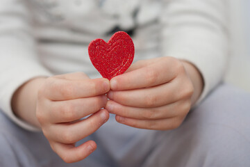 manos de niña sosteniendo un corazón de goma rojo. San Valentin horizontal. Espacio para escribir