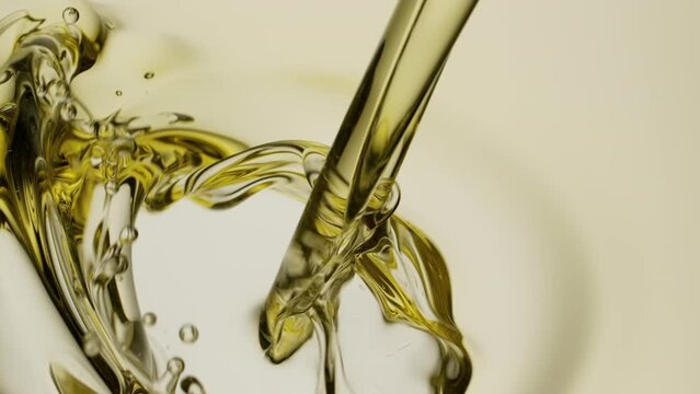 Macro crane shot of almond oil is being poured into pale yellow oil on white background | Abstract skin care cosmetics ingredients formulating concept