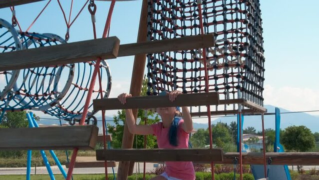 Teen have fun on rope children park. A hopefull teen girl have fun during climbing in the rope park under summer sun.
