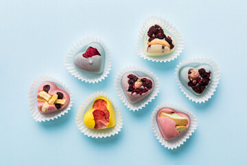 chocolate sweets in the form of a heart with fruits and nuts on a colored background. top view with space for text, holiday concept