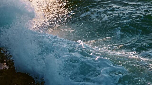 Foamy wave breaking coast outside closeup. Wild water crushing dangerous rocks