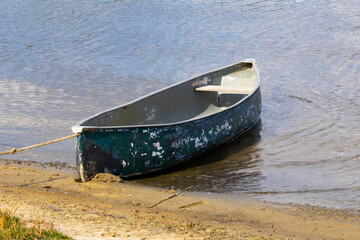 Old battered canoe tied up on a beach