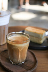 Dirty coffee with cake in coffee shop cafe and restaurant. Cold milk topped with hot espresso shot. on wooden table.