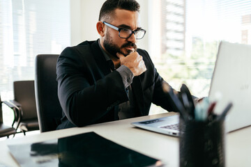 Obraz premium Young Brazilian businessman working on laptop in modern office