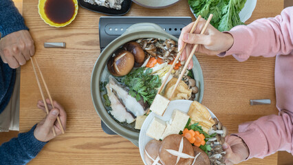 家庭で日本の鍋料理を食べる夫婦　イメージ