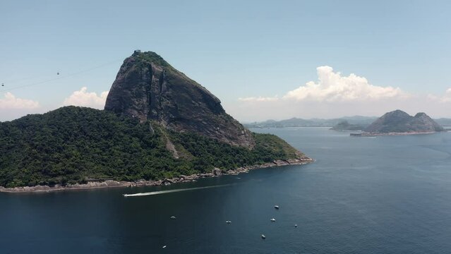 Aerial towards Sugarloaf Mountain with cable cars and panorama of Rio de Janeiro. Low angle shot above ocean