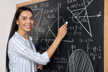 Happy teacher explaining mathematics at chalkboard in classroom