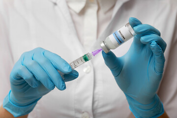 Doctor filling syringe with hepatitis vaccine from glass vial, closeup