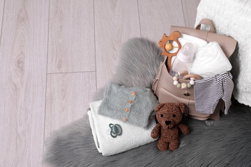 Mother's bag with baby's stuff on floor indoors. Space for text