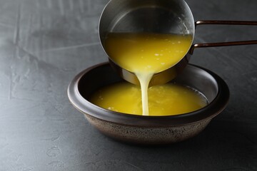 Pouring clarified butter into bowl on black table