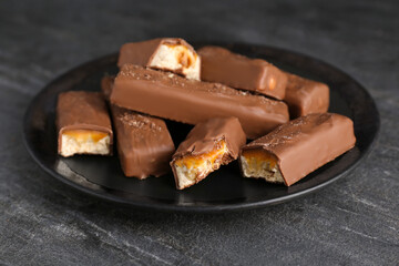 Plate with delicious chocolate bars on black table, closeup