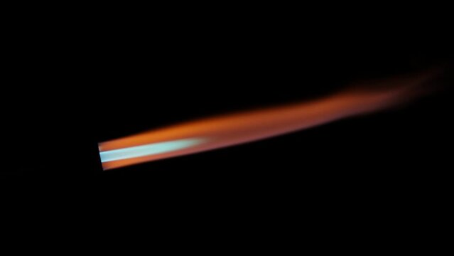 Close-up of flamethrower burner gas blowing fire with orange and blue flames on black background.