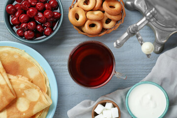 Flat lay composition with aromatic tea and treats on light blue wooden table