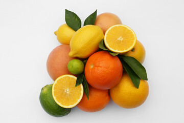 Different citrus fruits and leaves on white background, top view