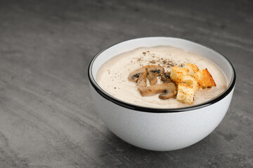 Delicious cream soup with mushrooms and croutons on black table. Space for text