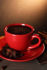 Cup of delicious hot chocolate, spices and coffee beans on wooden table