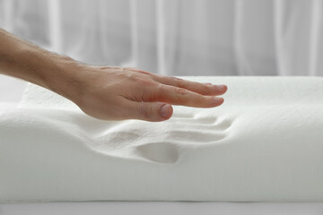 Man with orthopedic memory foam pillow indoors, closeup