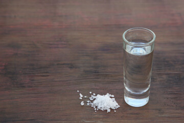 Mexican tequila shots with salt on wooden table. Space for text