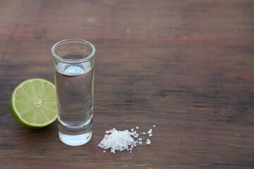 Mexican tequila shots with lime and salt on wooden table. Space for text