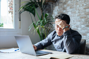 Stressed tired man in pain having strong terrible headache attack after computer laptop work,...