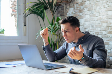 Unhappy young caucasian male worker in glasses look at laptop screen shocked by gadget breakdown or...