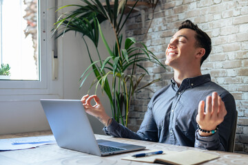 Serene office male employee sit at desk relaxing doing yoga, practice meditation to reduce stress...