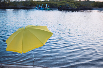 a yellow umbrella on the riverbank