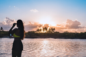 Fototapeta premium the silhouette of a woman dancing at sunset on the bank of a river
