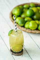 Brazilian drink Caipirinha on a white wooden table with lemons in the background.