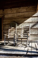 closeup of rocking chairs on wooden front porch of historic civil war era 1800s or 19th century southern log cabin in Callaway gardens in Georgia