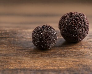 tasty black truffles on wood background, close up view.