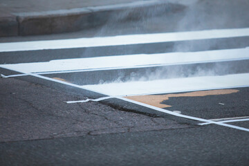 Process of making new road surface markings with a line striping machine, workers improve city infrastructure, demarcation marking of pedestrian crossing with hot melted paint on asphalt pavement